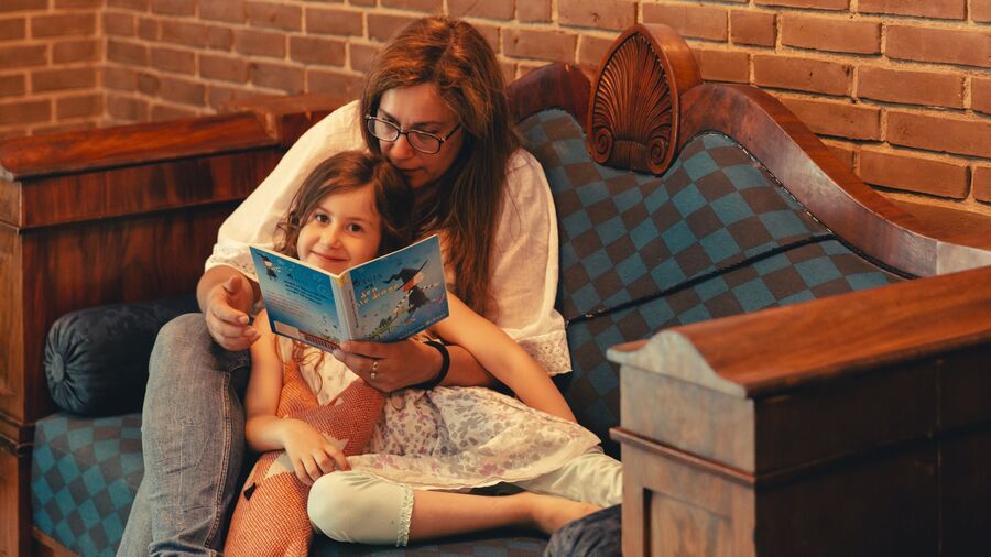 Barn får læst bog højt i sofa