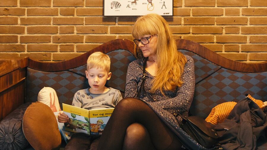 Barn og voksen læser i sofa