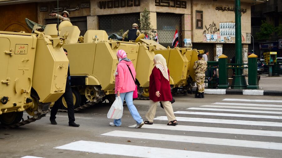 Foto fra dokumentarfilmen "I lyset af revolutionen": kvinder går mellem kampvogne