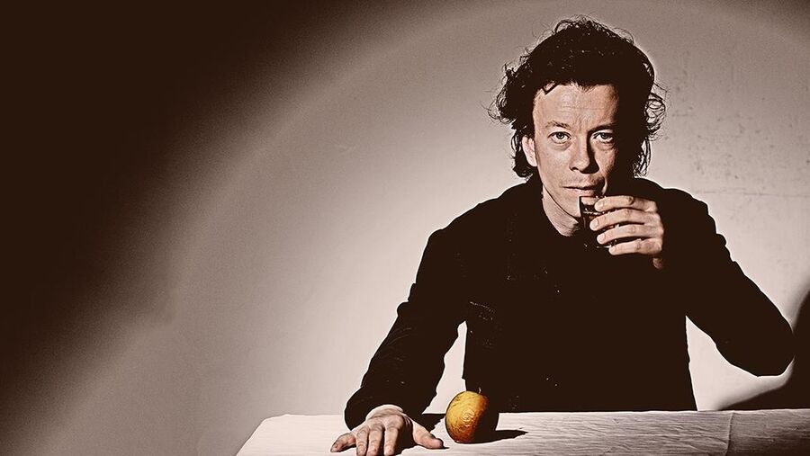 Musiker Peter Rosendal ved bord med æble på og glas i hånden