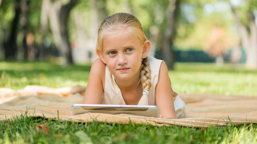 Du kan lære om naturen online - men også tage din viden med ud, som dette barn i en park med sin tablet.